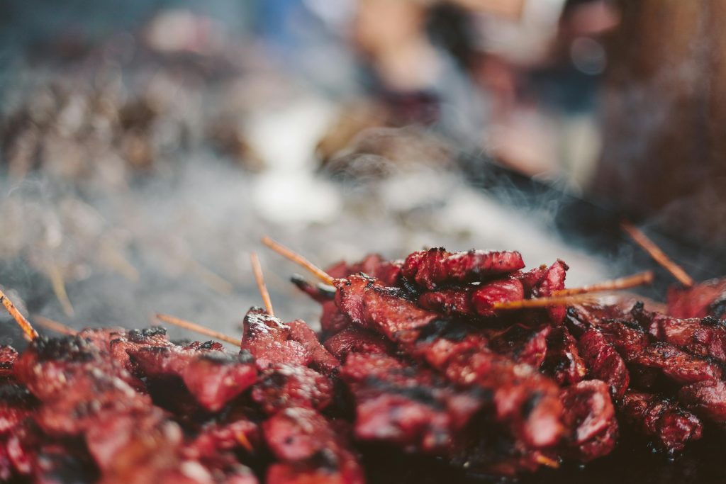 Close-up of delicious meat skewers sizzling on a grill with smoke.
